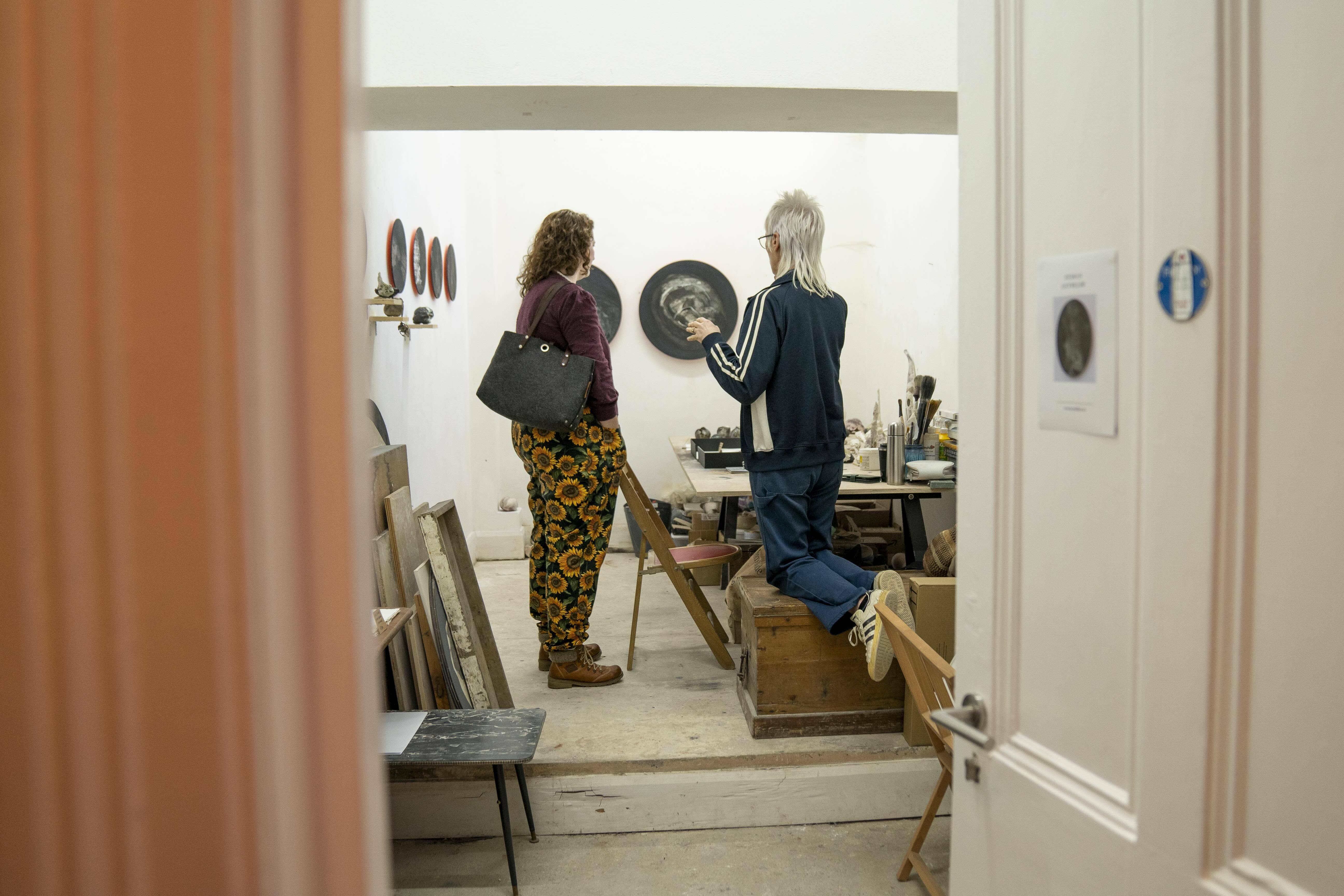 two women in a doorway looking at art