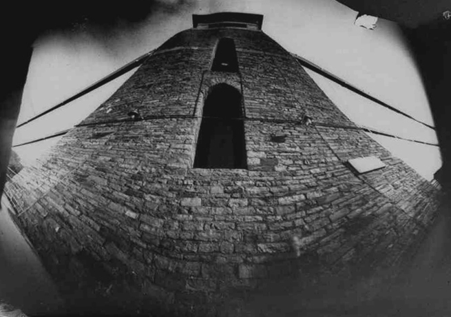 Black and white pinhole photograph of suspension bridge tower