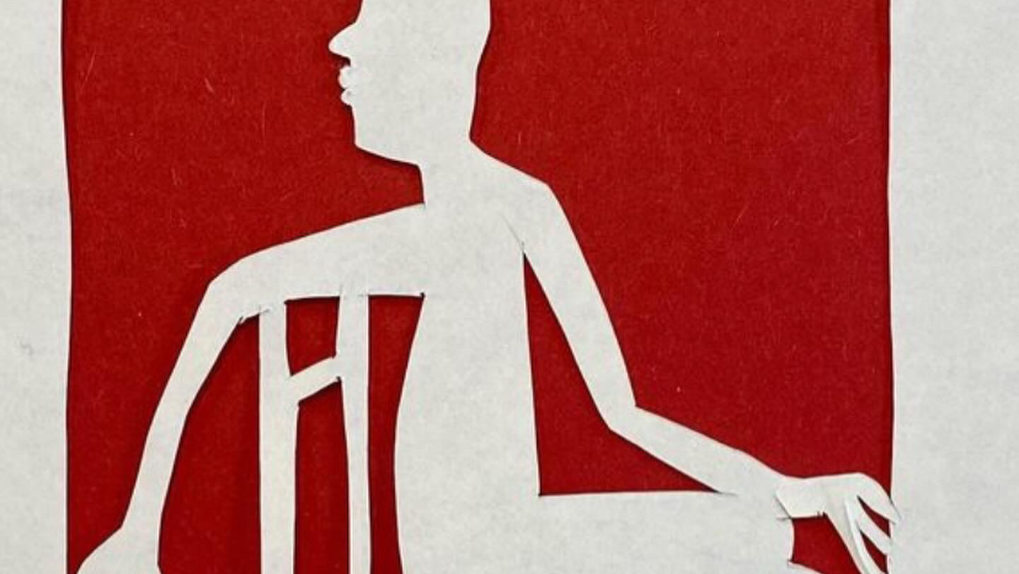 A white paper seated figure on a red paper background.