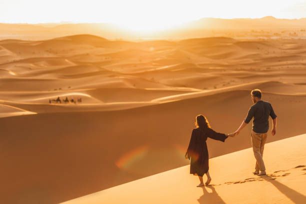 Couple walking in Sahara desert at sunset