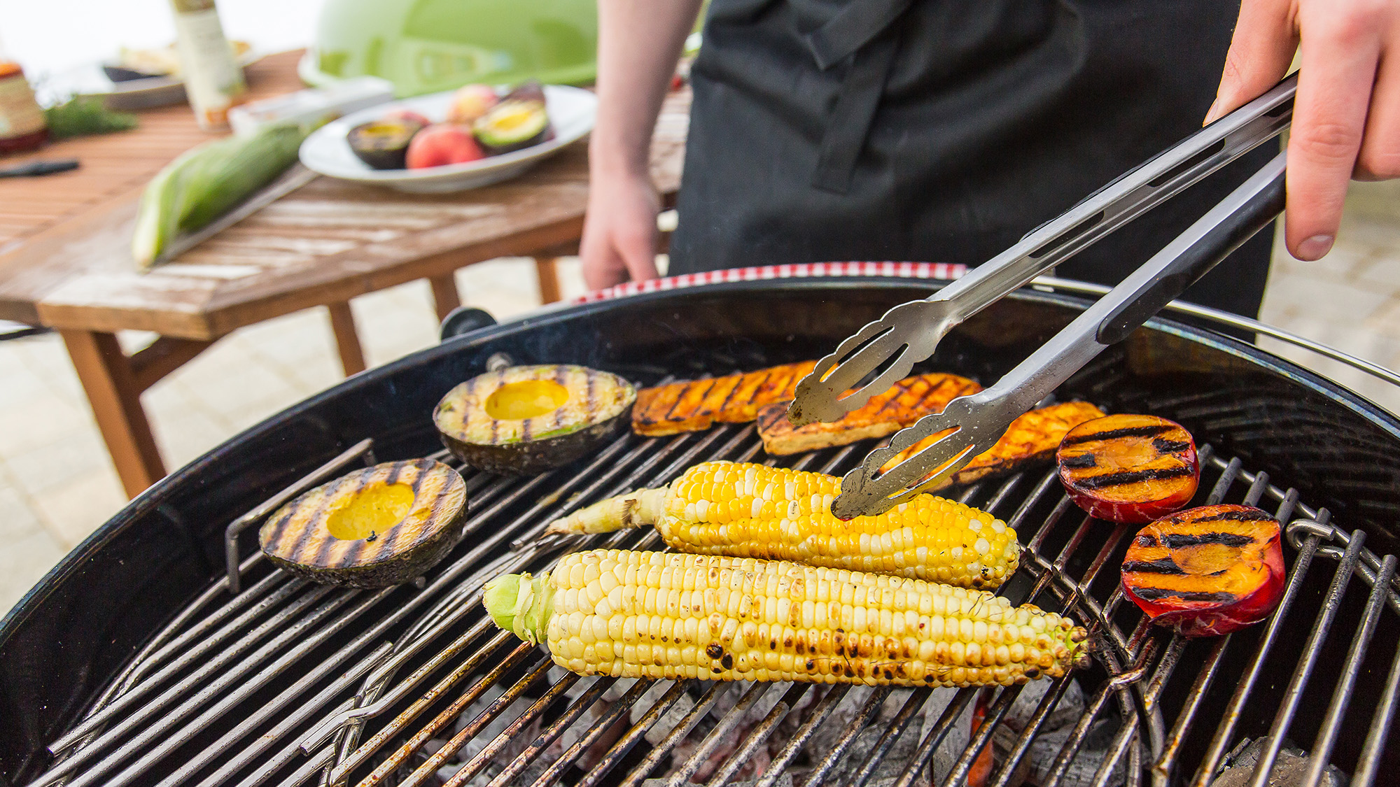 someone grilling corn, tofu, peaches, and avocados for a vegan BBQ