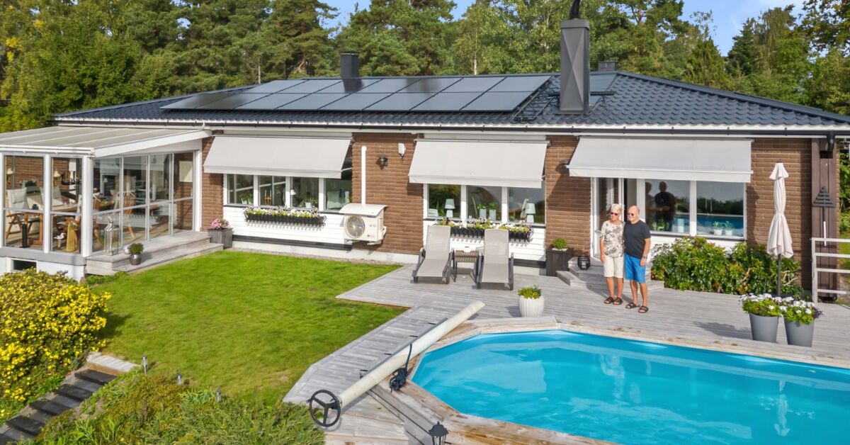 svarta solpaneler på villatak, solcellskunderna Barbro coh Kari framför sitt hus och bredvid sin pool