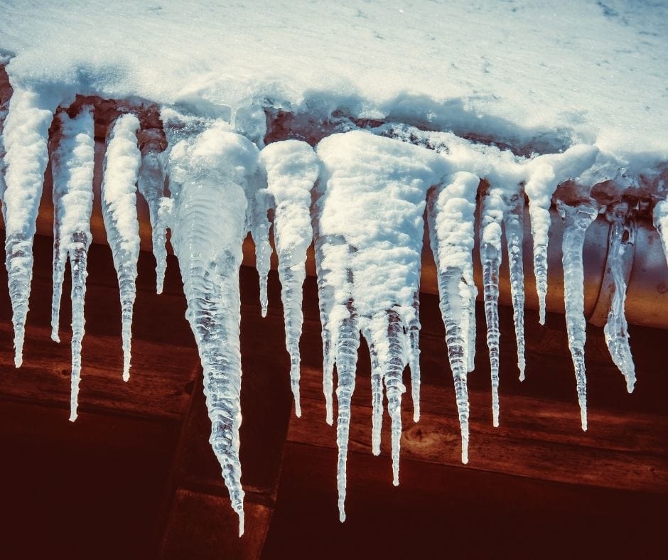 istappar och snö på tak till rött trähus