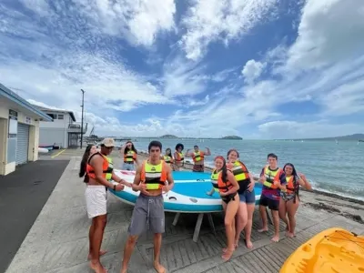 Des élèves d’Anglais + High School prêts pour une séance de paddle sur une plage d’Auckland