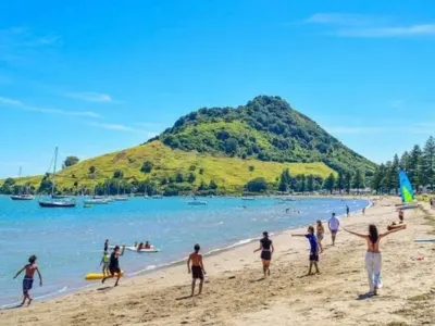 Studenti internazionali sulla spiaggia di Mount Maunganui, con Mauao alle spalle