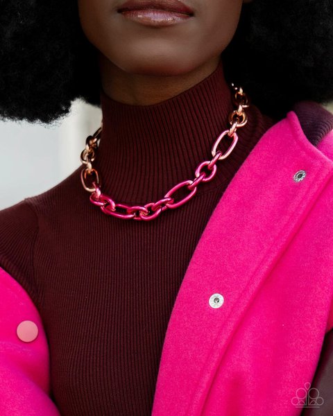Closeup of a woman wearing a dark mock neck top under a pink coat with A chunky pink paparazzi acces…