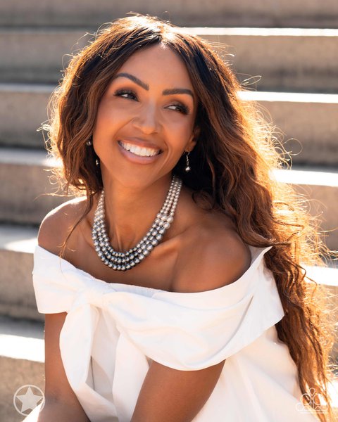 Woman with long brown hair wearing white off shoulder dress and lady in waiting layered pearl neckla…