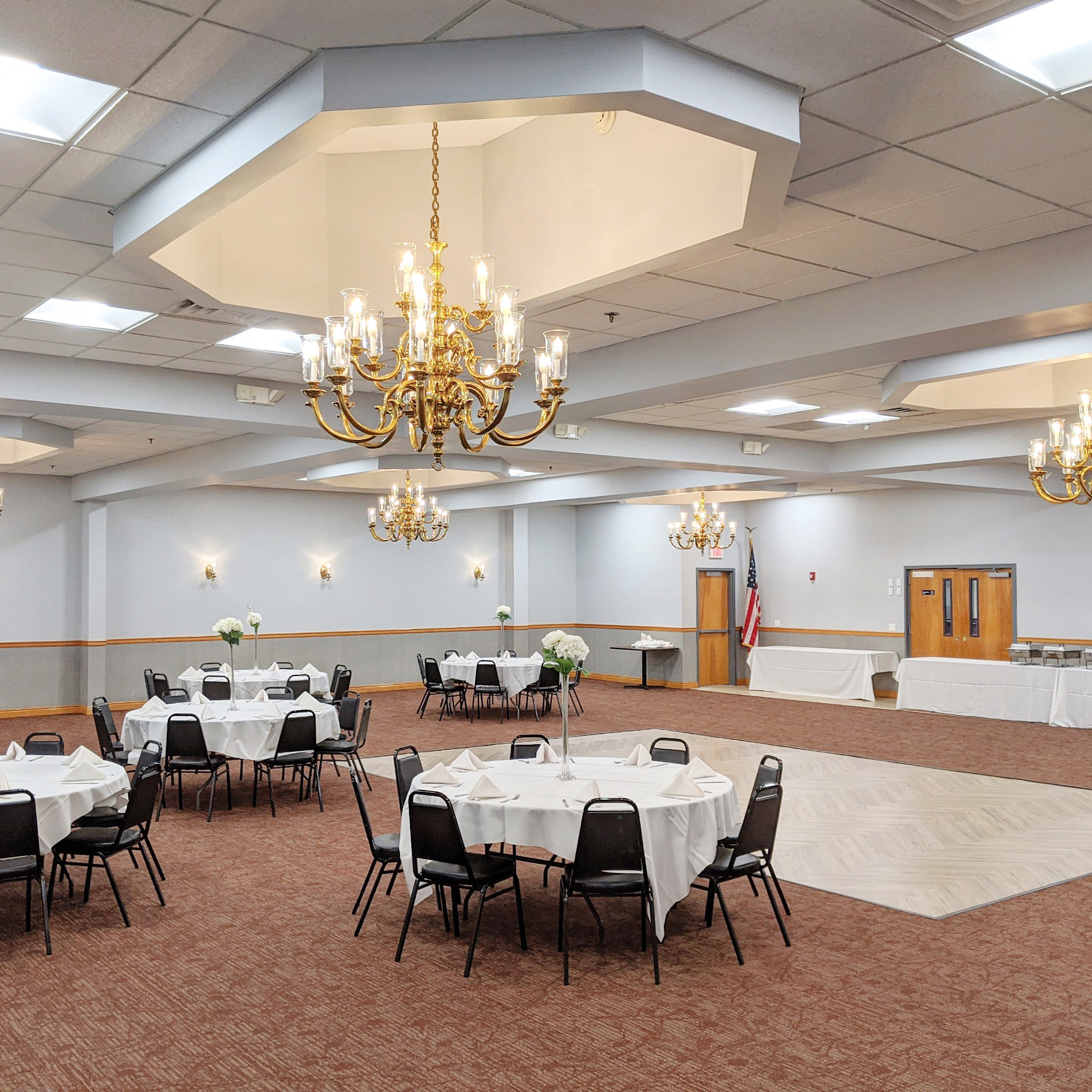 Banquet room set with round tables, floral centerpieces and chandelier lighting