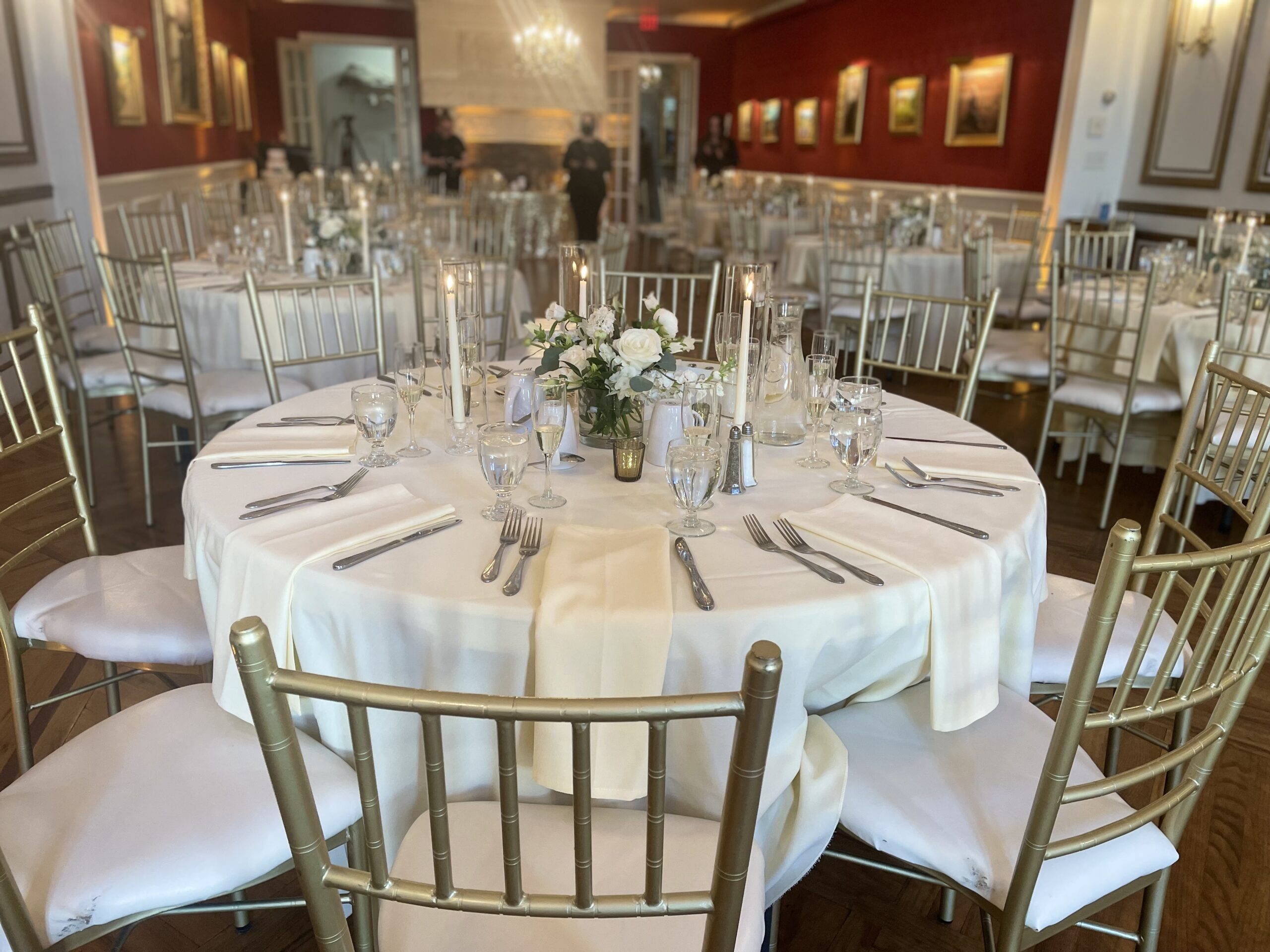 Reception table with cream linens, white roses and gold chiavari chairs