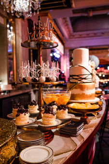 Lavish dessert display featuring cake pops, miniature pastries and a multi-tiered wedding cake