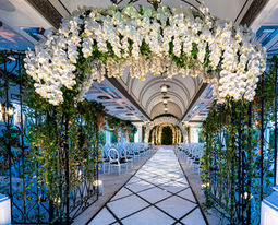 Indoor ceremony aisle lined with white flowers and green vines overhead