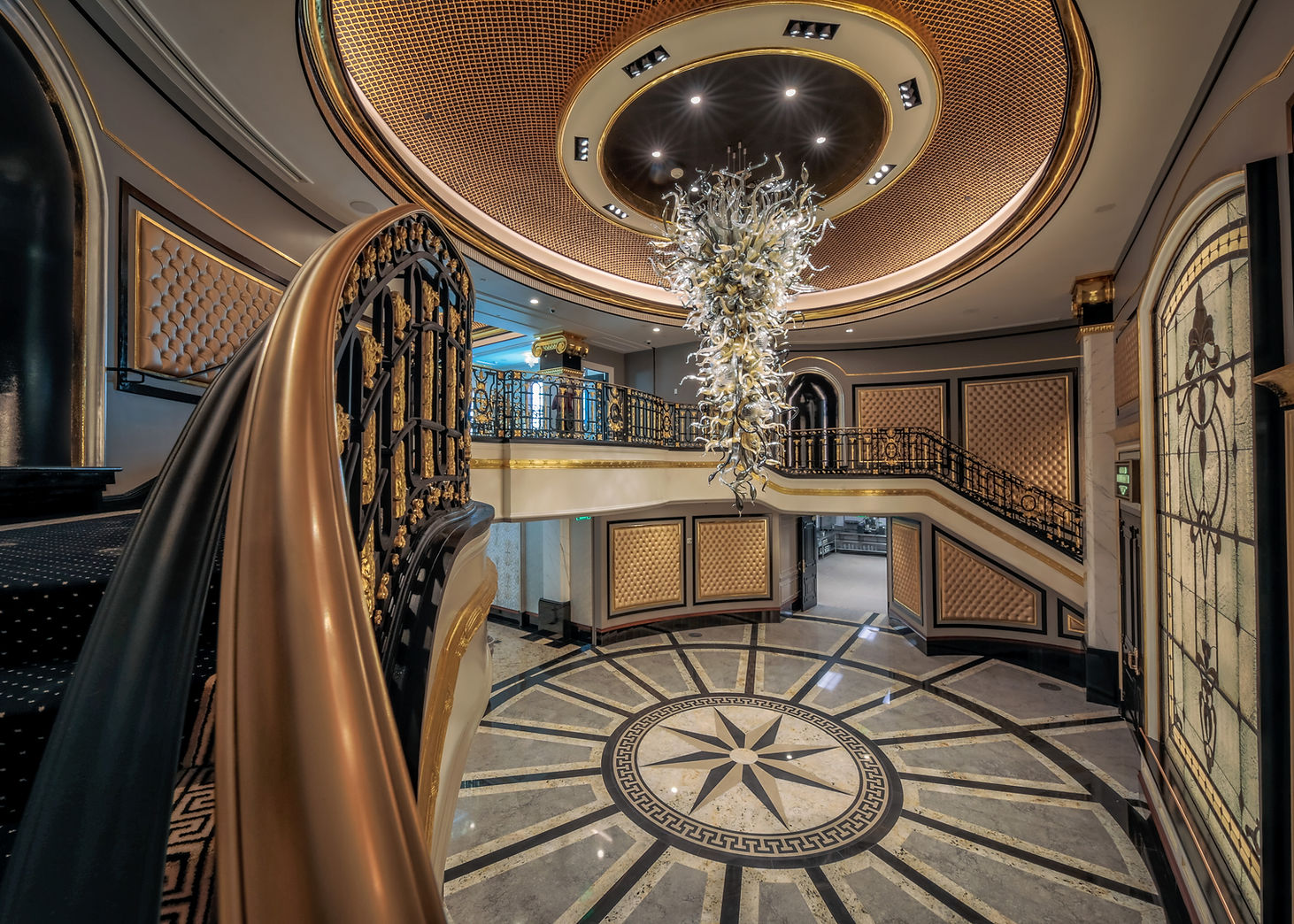 Grand foyer with gilded ceiling, glass chandelier and starburst tile floor where guests arrive