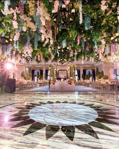 Ballroom with a decorative floor monogram and hanging floral ceiling installation