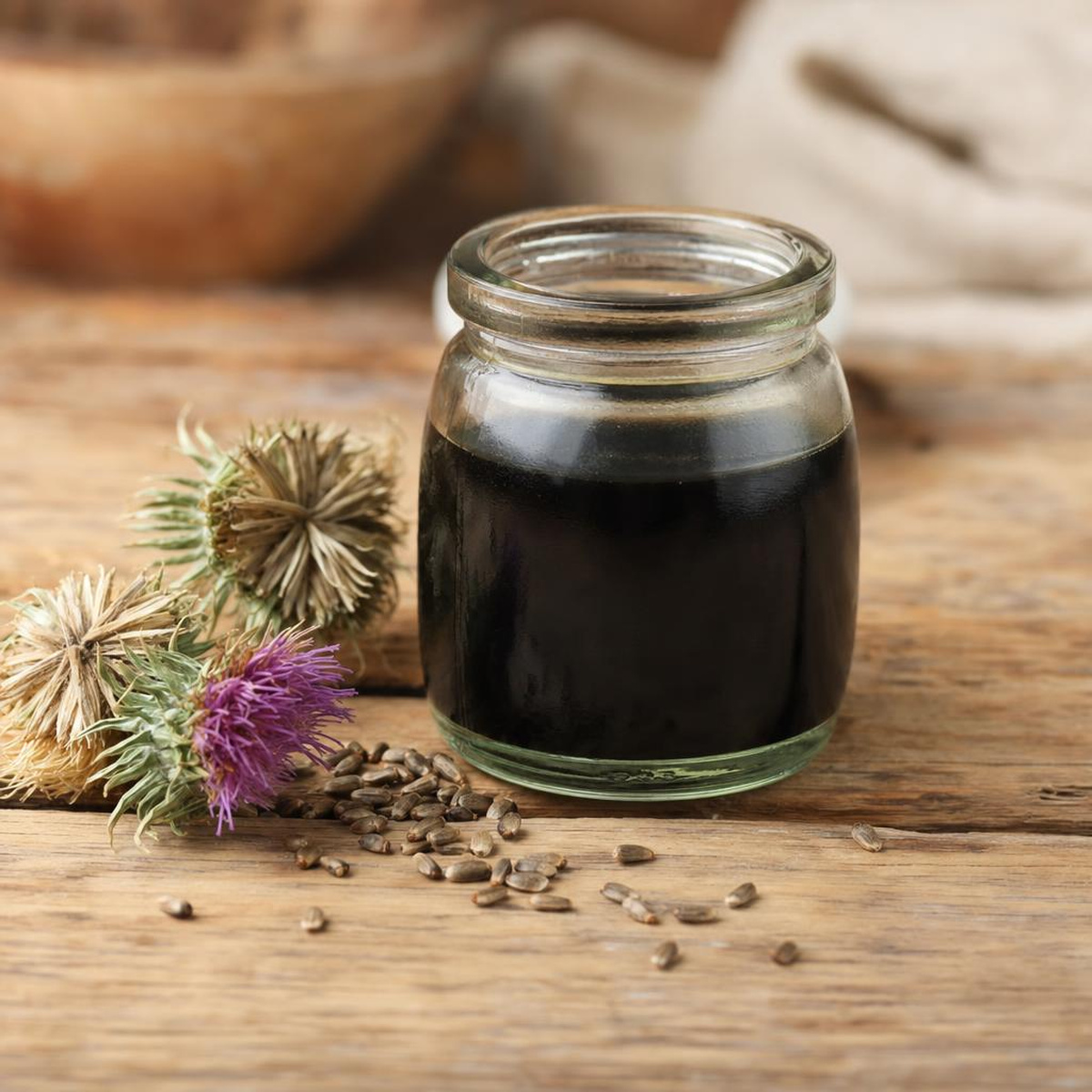 A jar of dark, cold-pressed milk thistle tincture on a farmhouse table