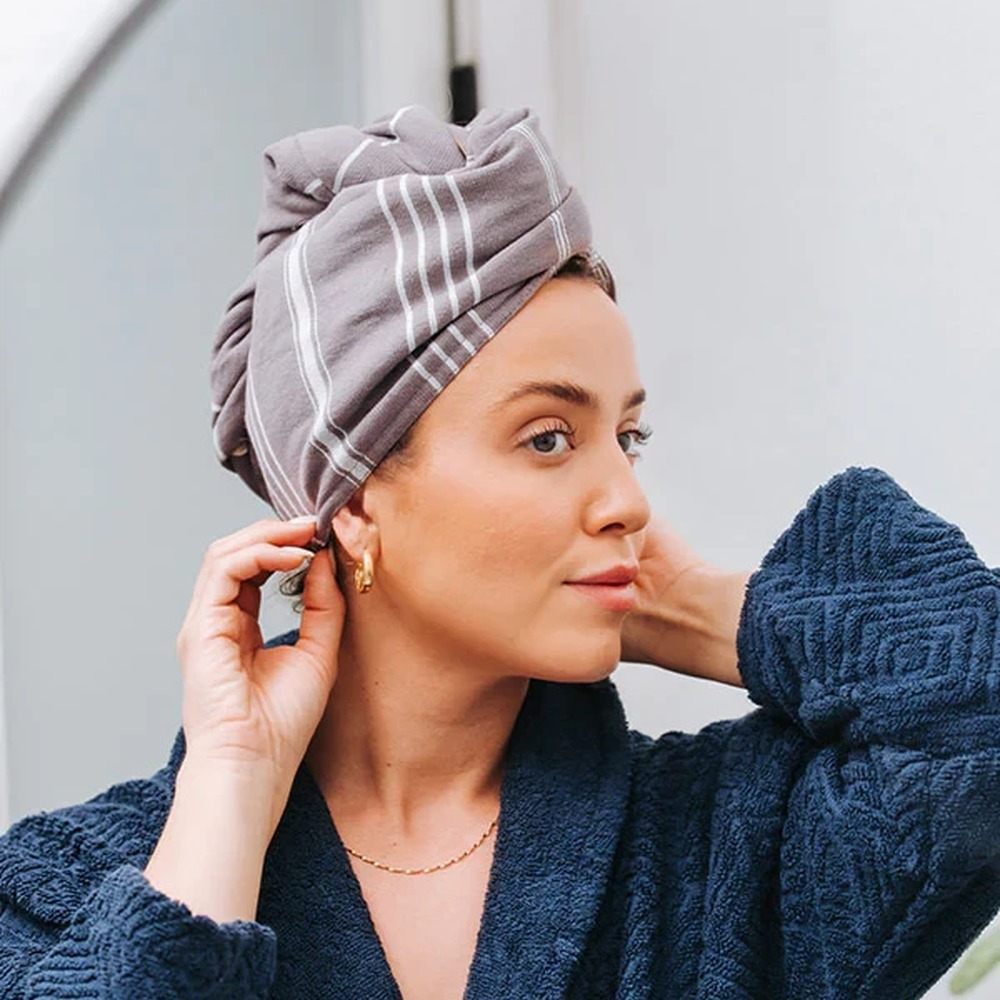 A woman wearing the Sand Cloud hair towel wrapped over freshly washed hair
