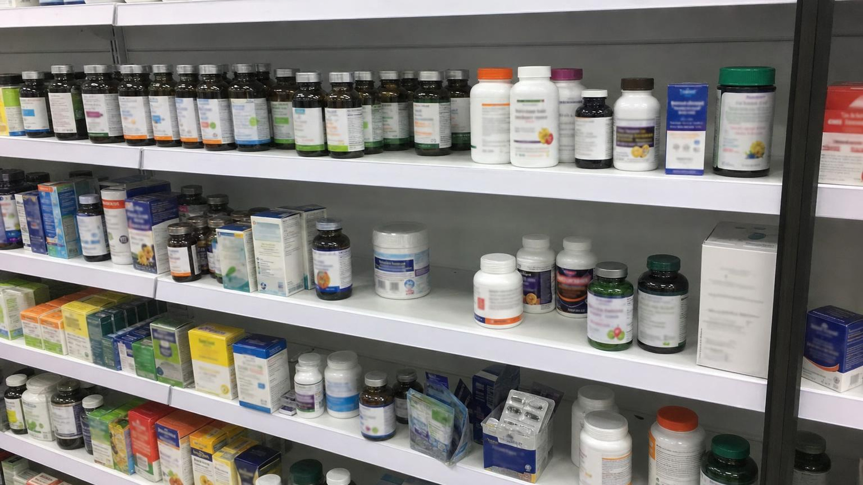 A shelf of ordinary garlic supplement tubs in a pharmacy aisle