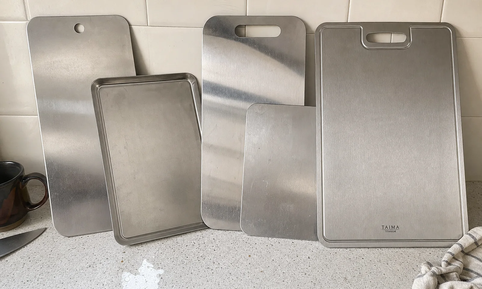 All five titanium cutting boards we tested, propped up side by side on a kitchen counter