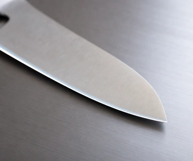 A chef's knife edge resting on the titanium surface