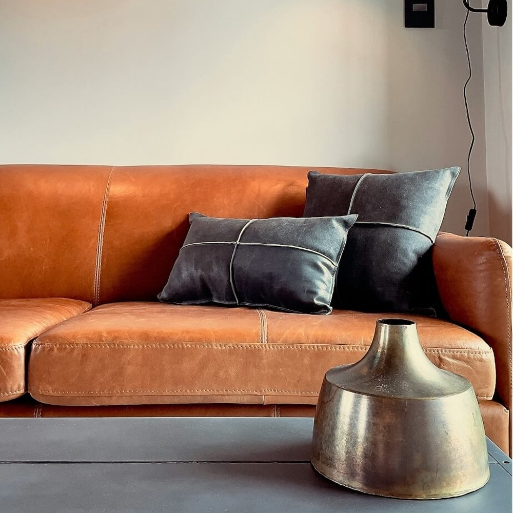 A tan leather sofa with an even, restored color in a styled room