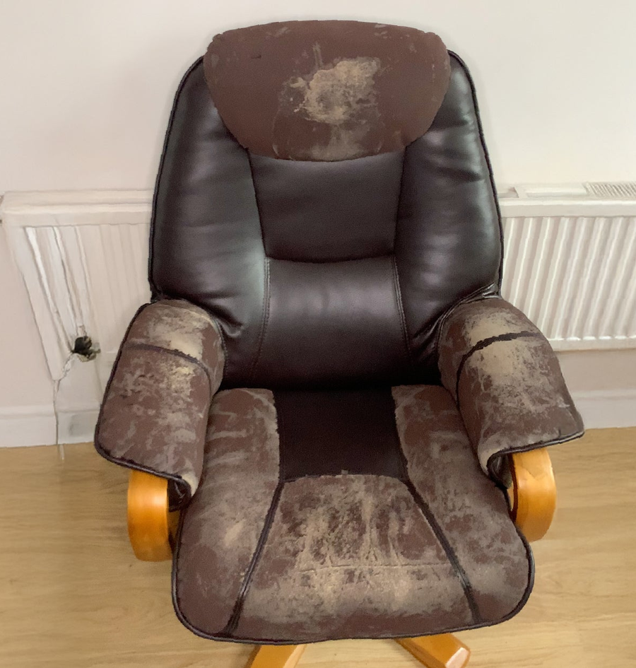A leather recliner with the color worn away across the seat and back