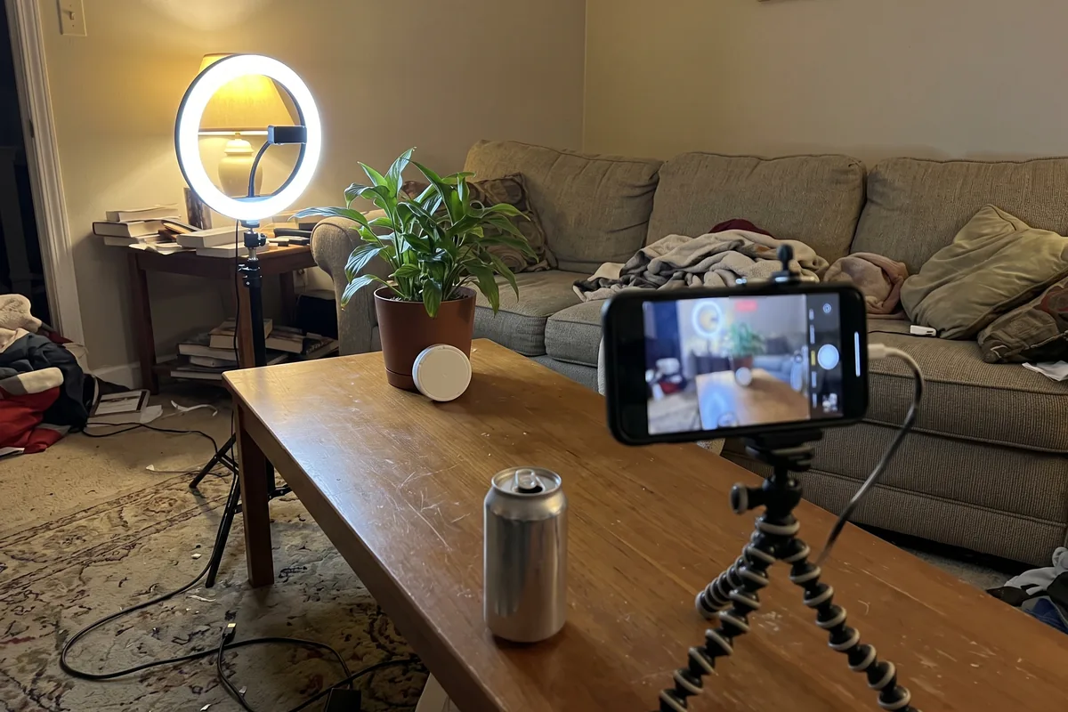 A ring light and a phone on a tripod set up in a living room to film a pouch tin
