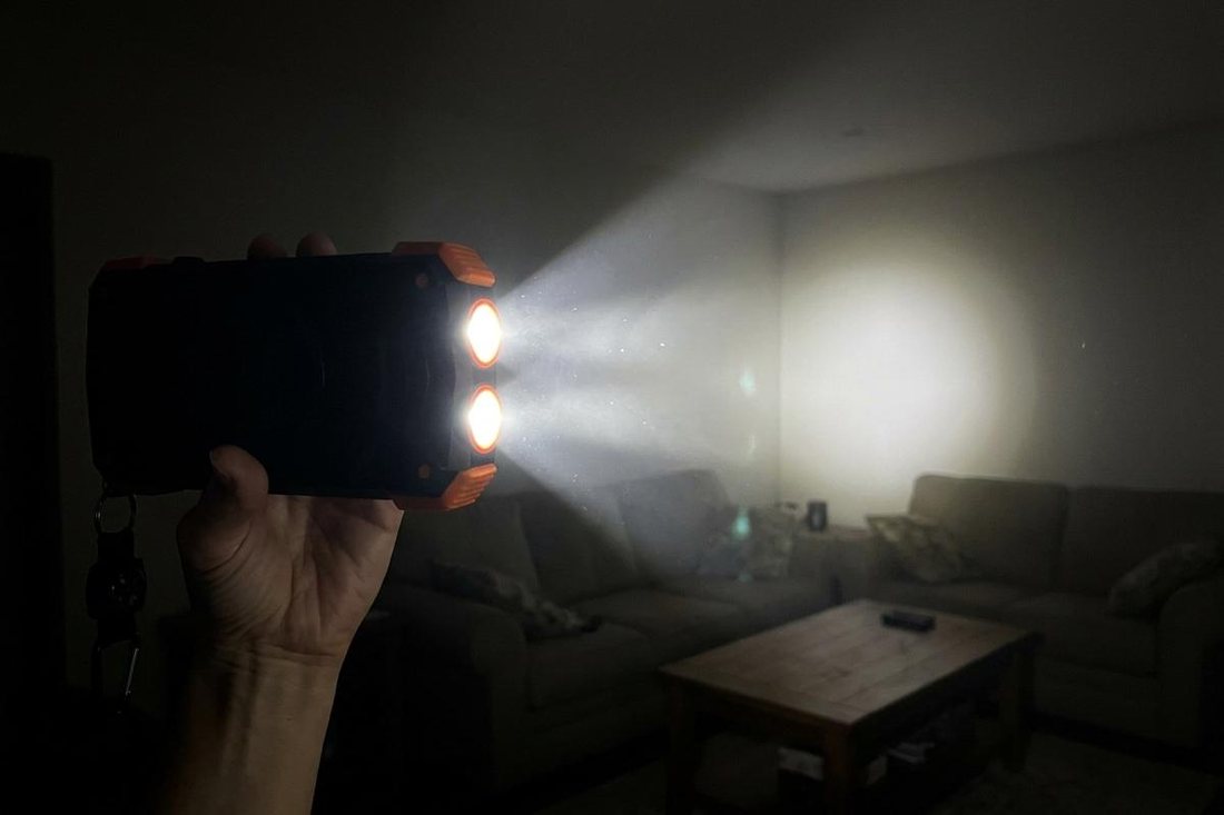 The power bank's twin LED flashlight lighting up a dark living room during a night-time outage