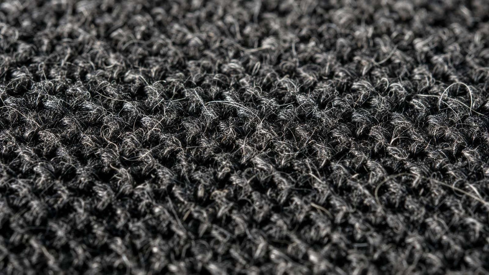 Close-up of cat hair packed deep into the weave of a worn seat cushion