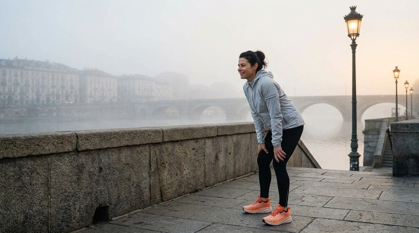 Una runner riprende fiato sul lungo Po avvolto nella nebbia del mattino