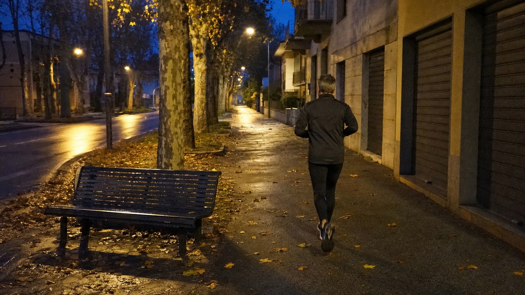 Un uomo esce a correre all'alba in una strada illuminata dai lampioni, a ottobre