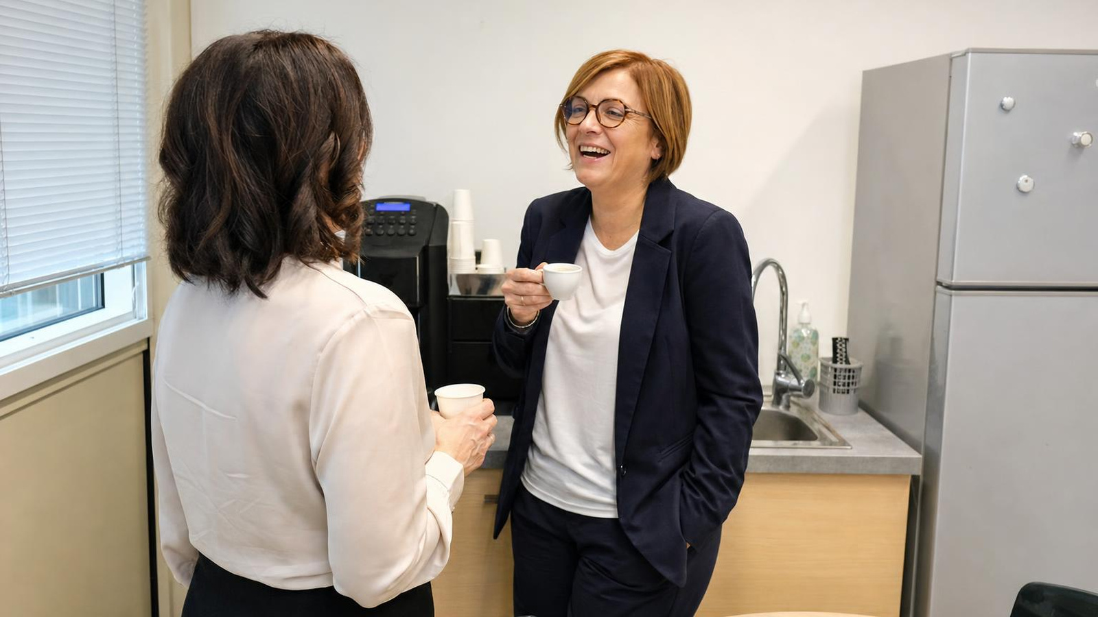 Due colleghe chiacchierano davanti alla macchinetta del caffè in ufficio