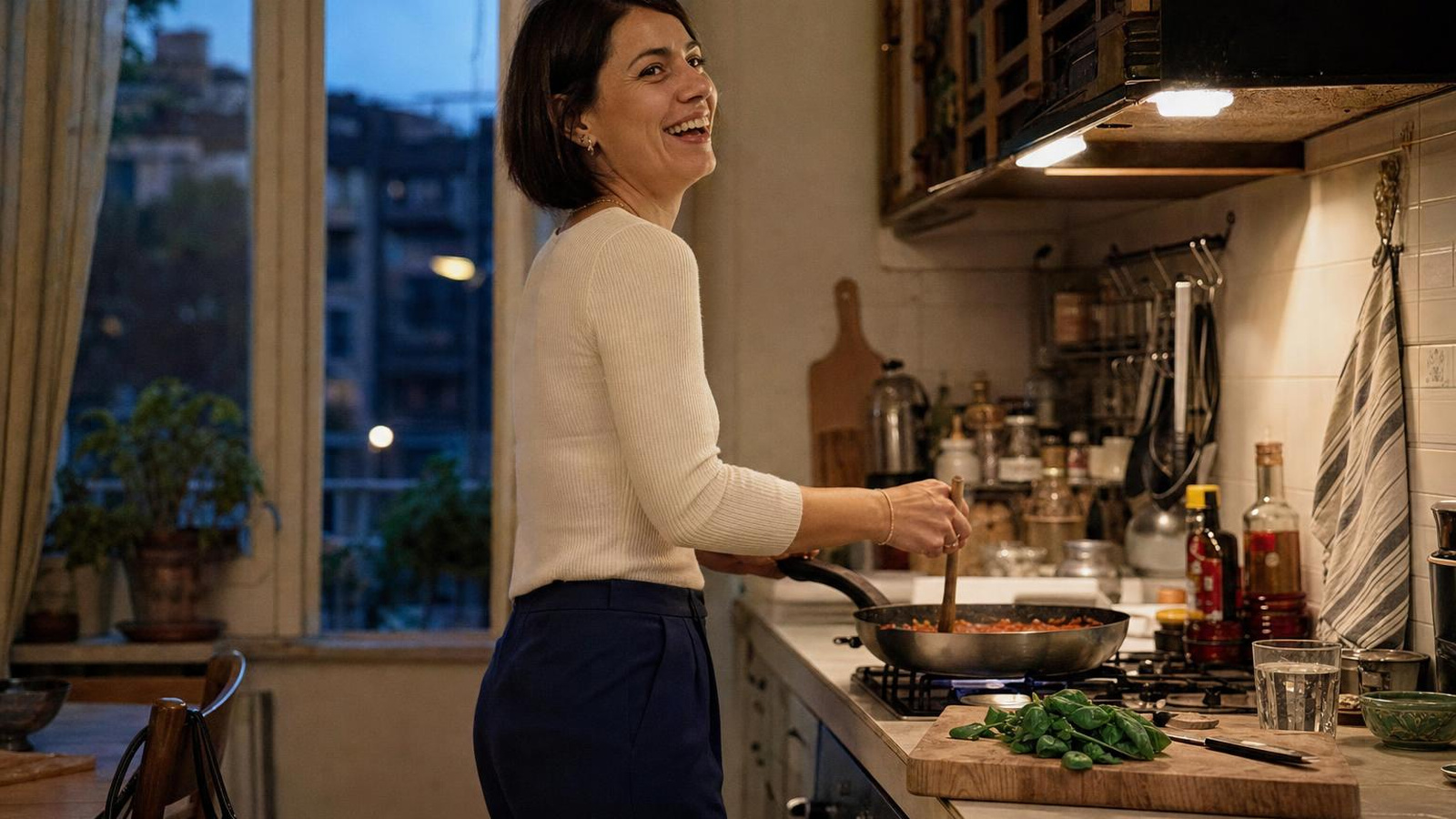 Donna in cucina la sera, ancora vestita da lavoro, rilassata