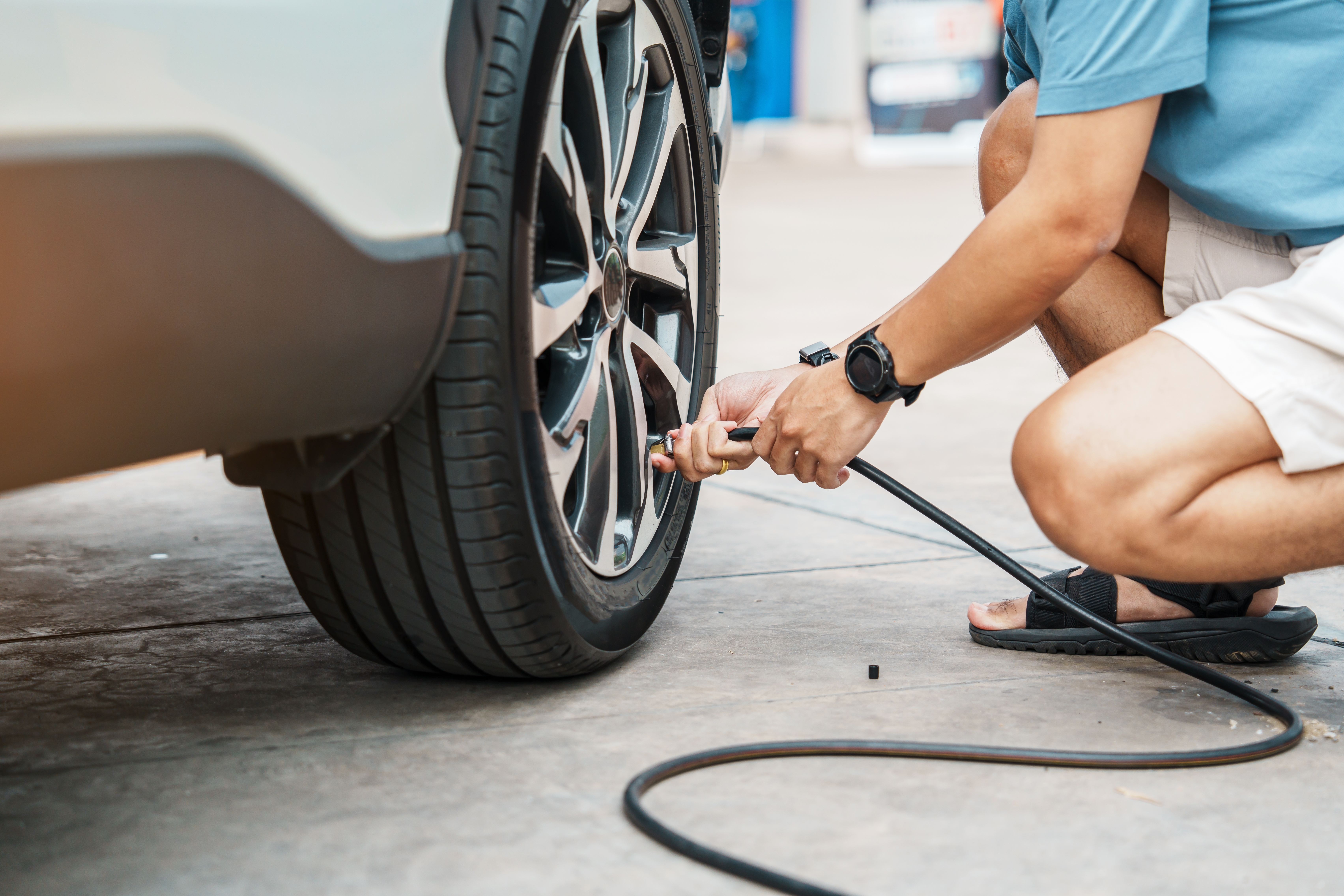 Person checking the tire pressure on a car tire.