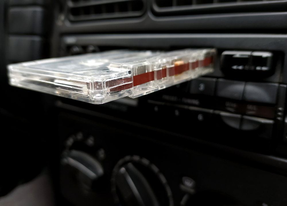 Close-up of a cassette tape partially inserted into a car's cassette player, showcasing the vintage audio system.