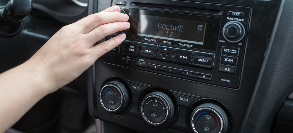 driver adjusts volume on their car's stereo
