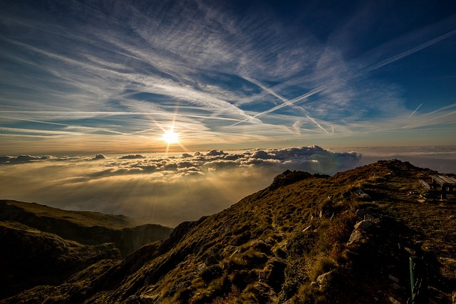 Sun rising over clouds and mountain