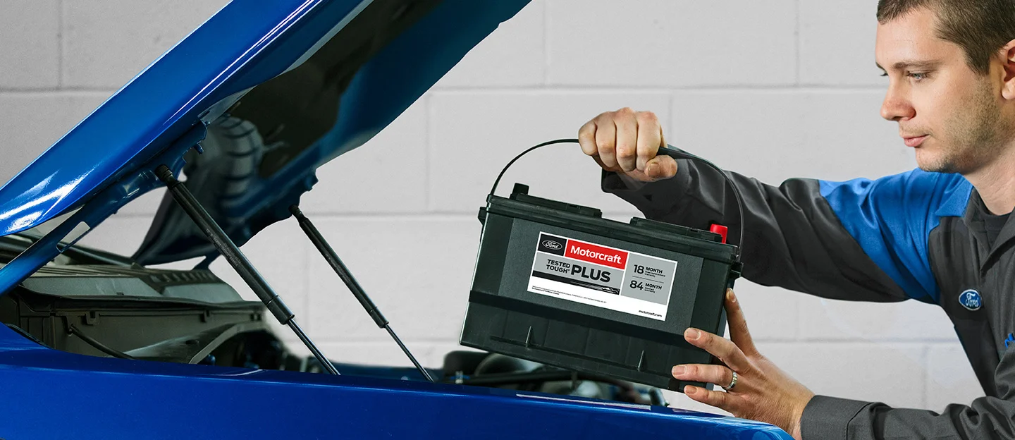 image of ford service employee installing new battery into blue vehicle