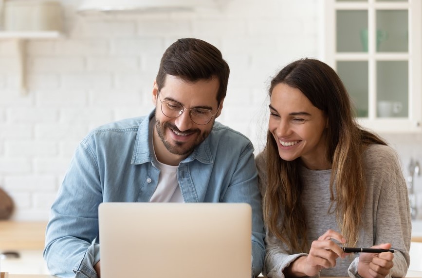 smiling couple researching used SUVs on their laptop together