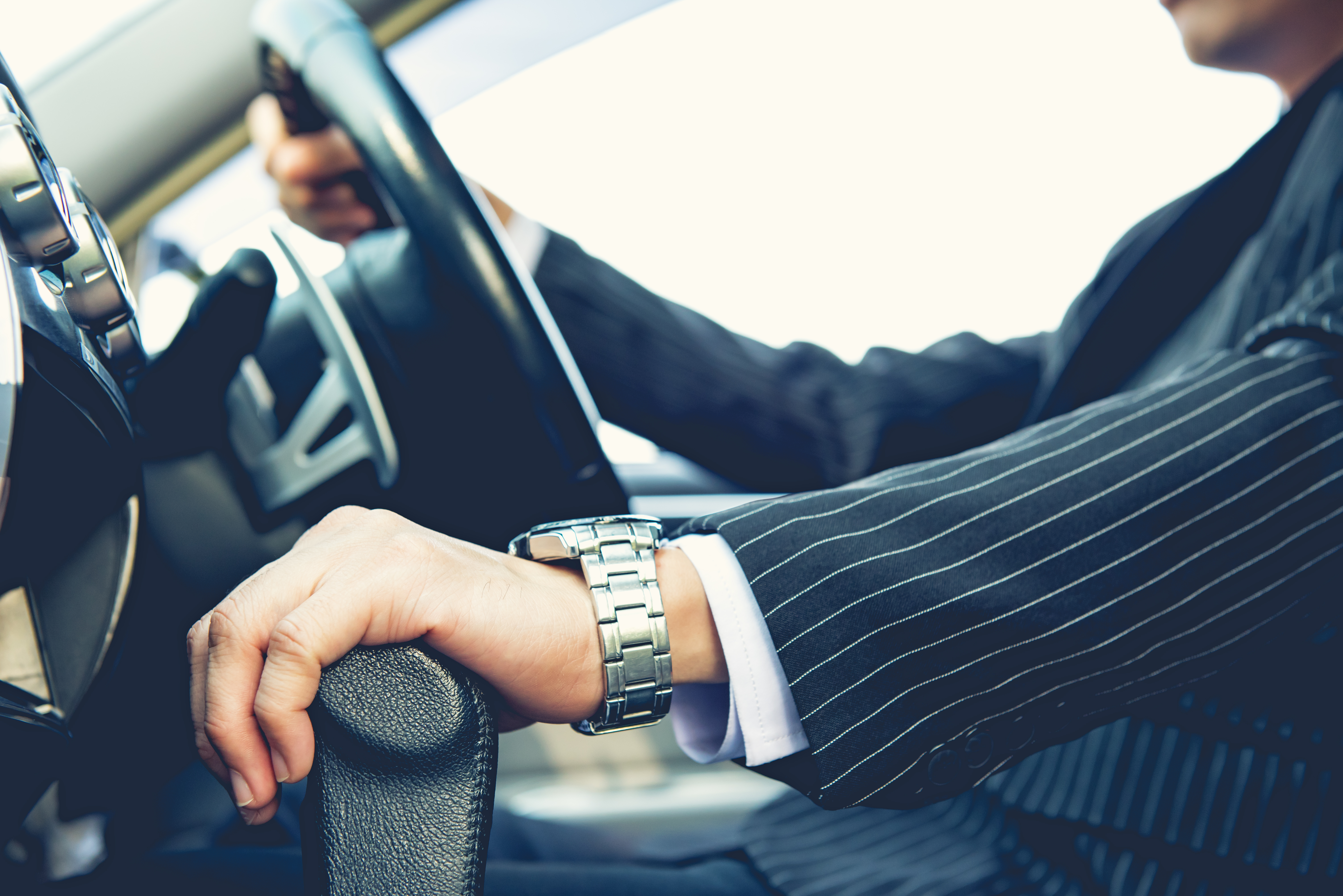 man wearing watch with hand on steering wheel