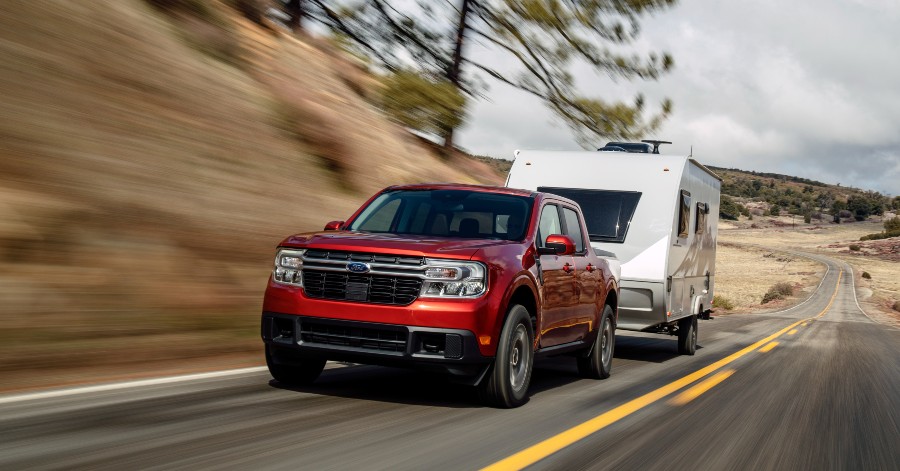 front view of a red 2022 Ford Maverick towing a camper