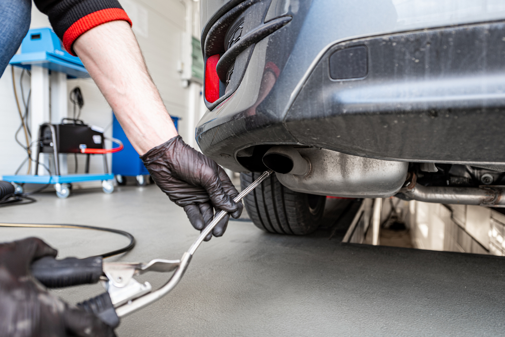 emissions testing aparatus being inserted into an exhaust pipe by a mechanic