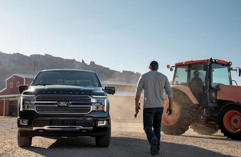 Man Walking Next to Black 2024 Ford F-150 Platinum and Tractor