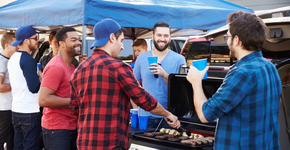 guys around a grill at a tailgating party