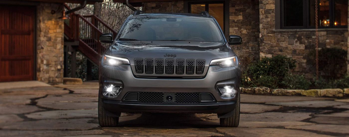 A grey 2023 Jeep Cherokee Altitude Lux is shown from the front parked on a driveway.