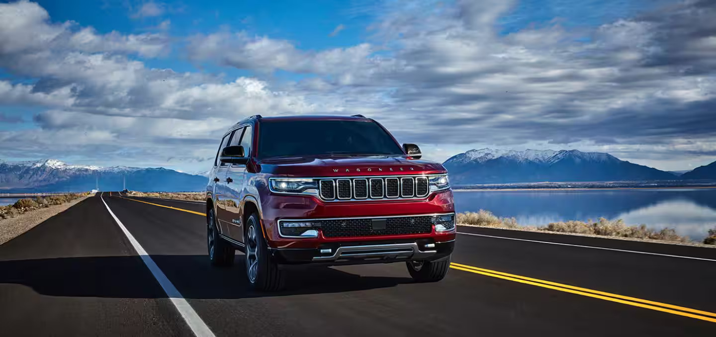 A red jeep wagoneer driving down a road.