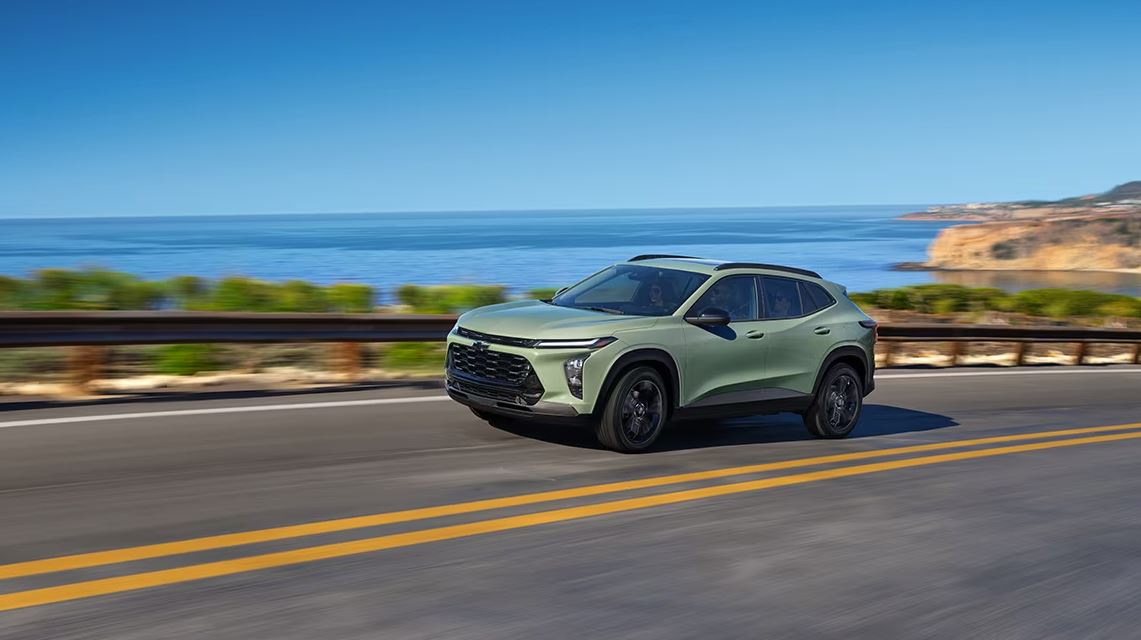 Cacti green 2024 Chevrolet Trax driving on a road along the shoreline
