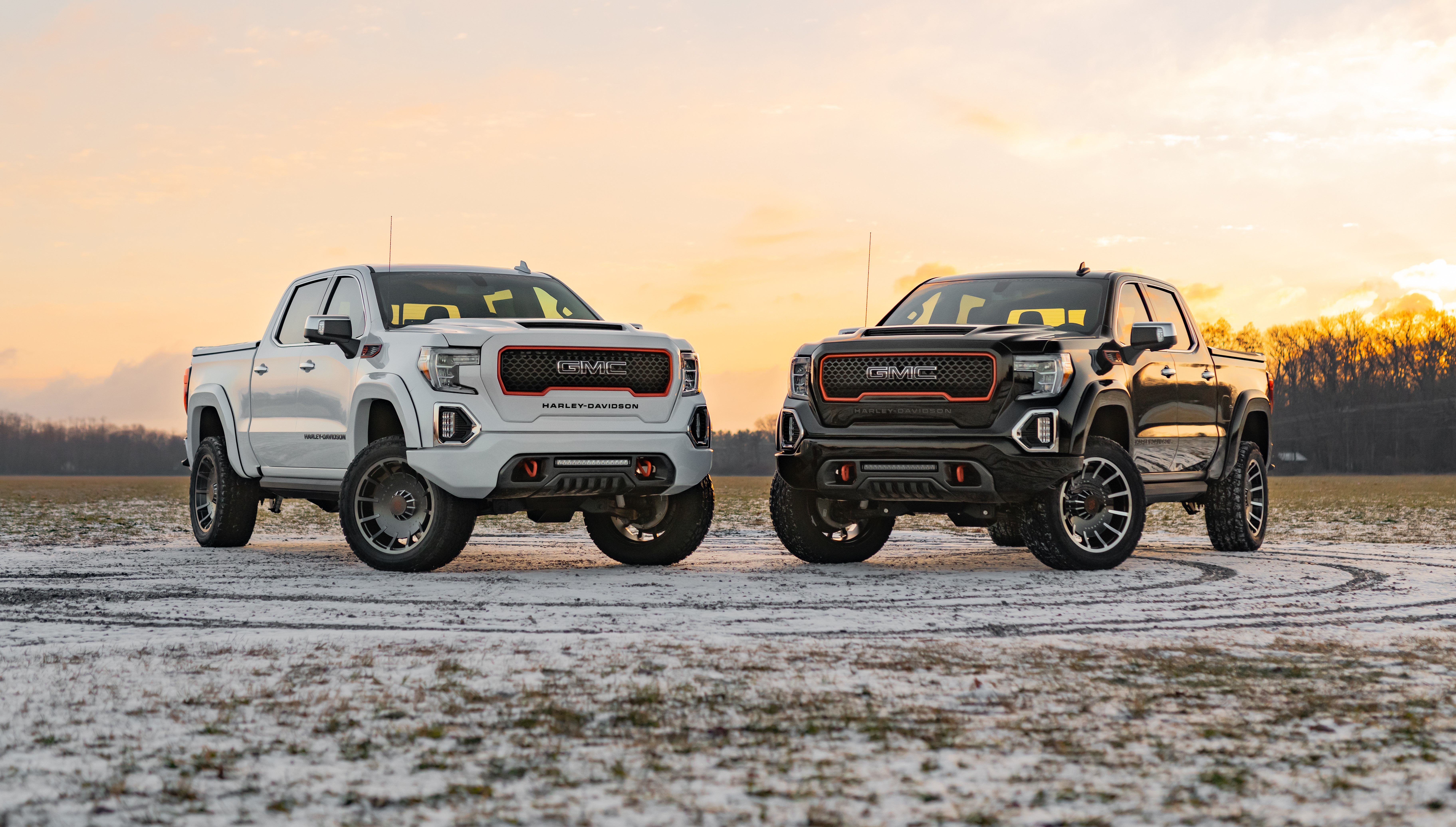 Two black and white GMC Harlay Davidson Trucks in a snowy field