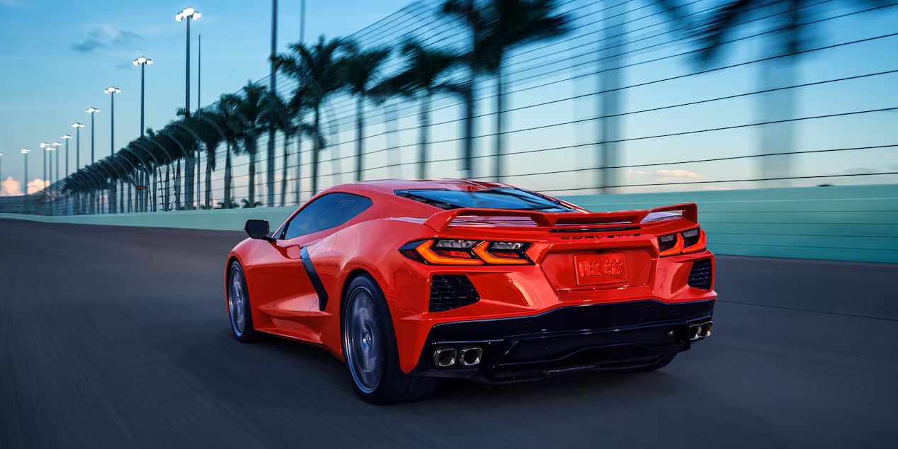 an orange red performance car driving on a racetrack