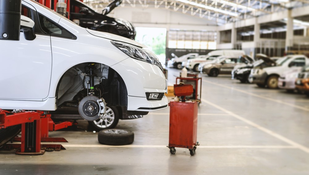 white car on an auto service lift without the passenger side tire