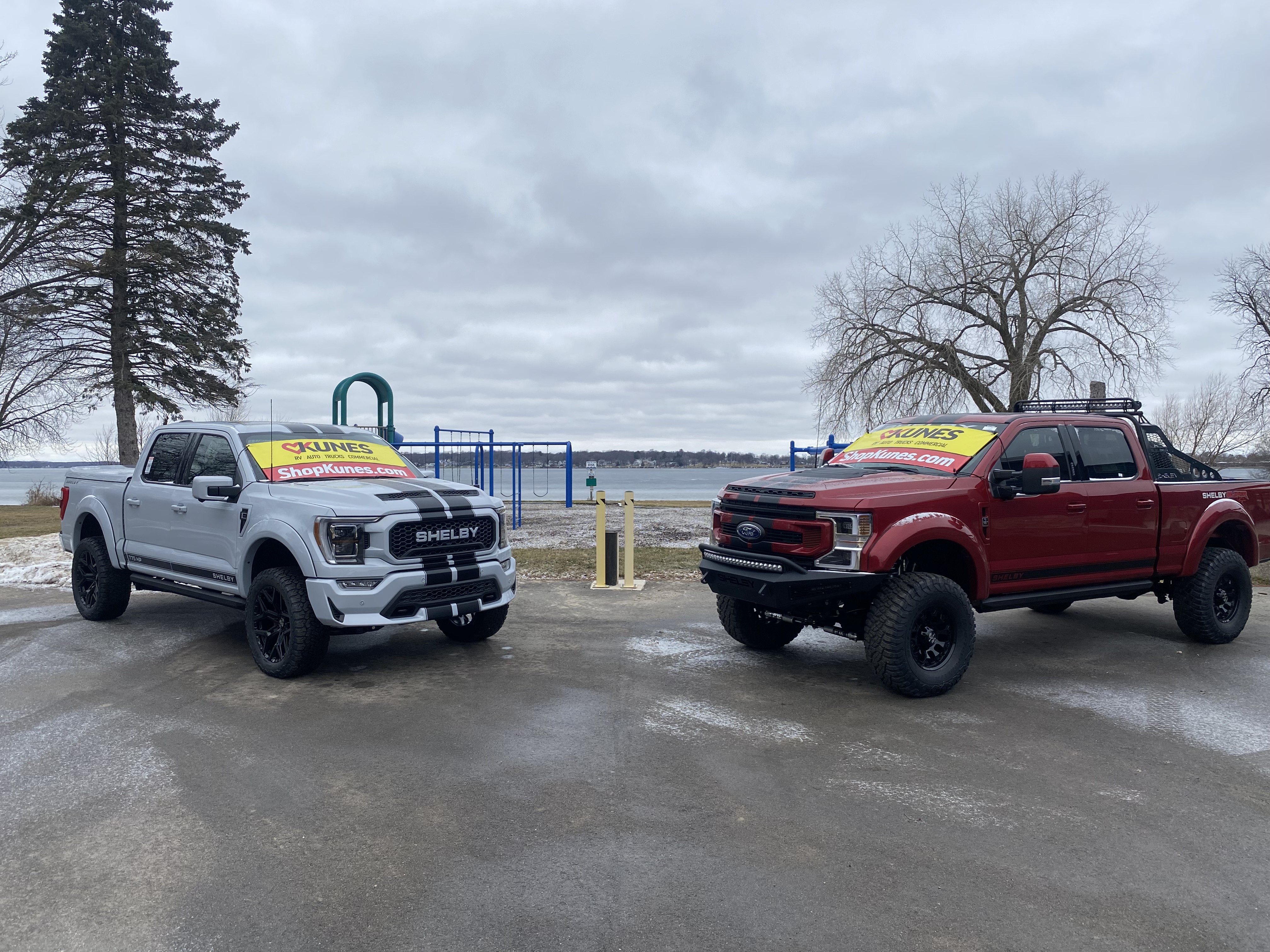 Two Kunes trucks posing in front of playground with Delavan Lake in the background