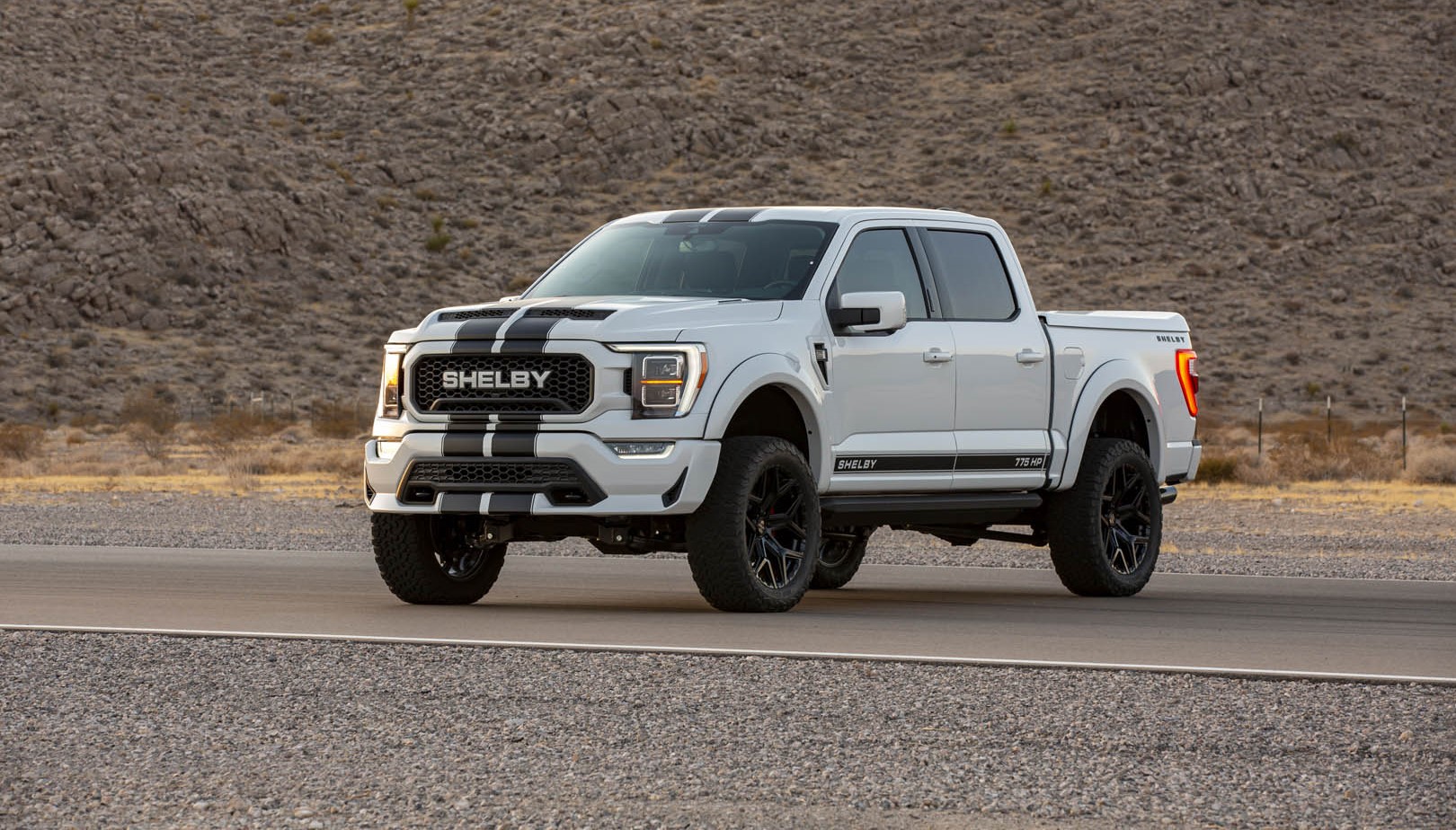 White Ford Shelby Truck with black stripes on a dirt road